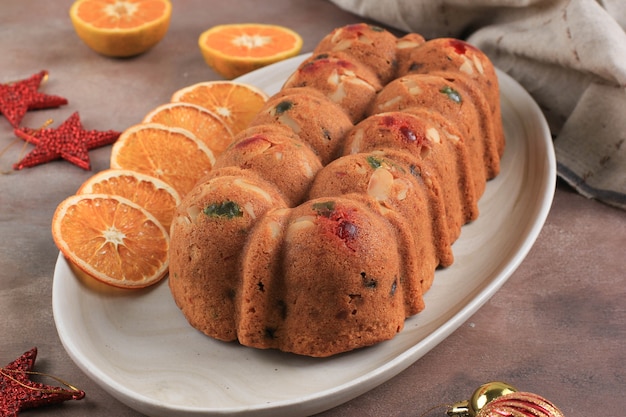 Caseiro rum pudim de bolo de frutas secas de Natal para festa em família. Servido em mesa de cimento marrom com sunkist seco