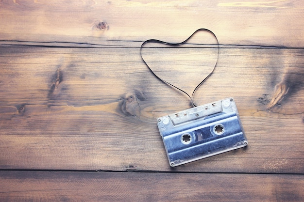 Casete de audio con cinta en forma de corazón sobre fondo de madera