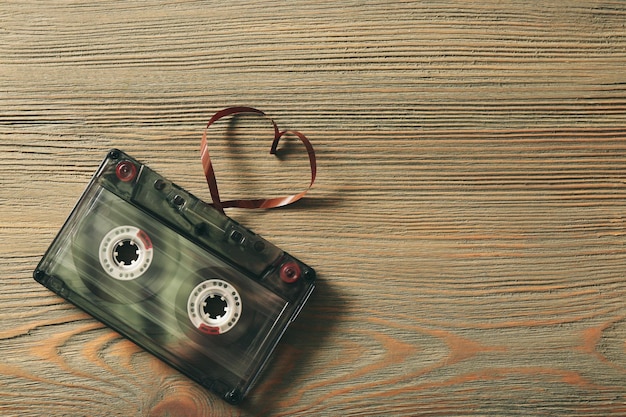 Casete de audio retro con cinta en forma de corazón sobre fondo de madera