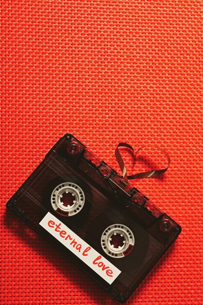 Foto casete de audio retro con cinta en forma de corazón sobre fondo de tela roja