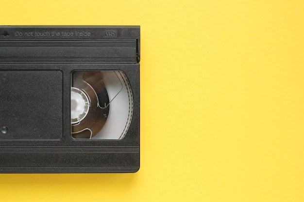 Casete grabador de cinta de vídeo VHS negro sobre fondo amarillo. Vieja tecnología obsoleta para grabación de cinta