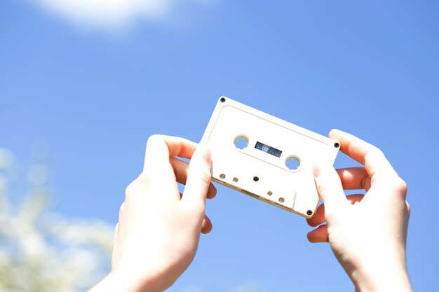 Casete en manos de la niña contra el cielo azul