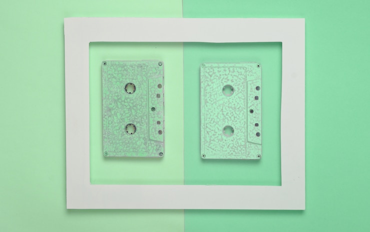 Foto casetes de audio de los años 80 en un marco blanco sobre un pastel de color.