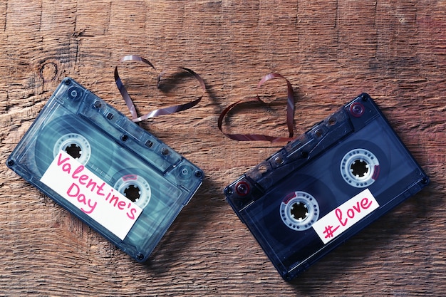 Casetes de audio retro con cintas en forma de corazones sobre fondo de madera