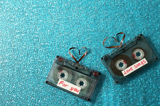 Casetes de audio retro con cintas en forma de corazones sobre fondo de textura azul