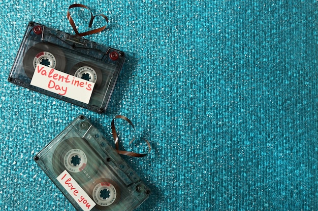 Casetes de audio retro con cintas en forma de corazones sobre fondo de textura azul