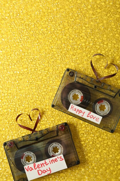 Casetes de audio retro con cintas en forma de corazones sobre fondo texturizado amarillo