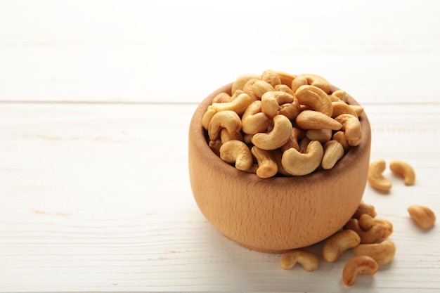 Cashew-Nüsse auf Holzschale auf weißem Hintergrund. Vertikales Foto.