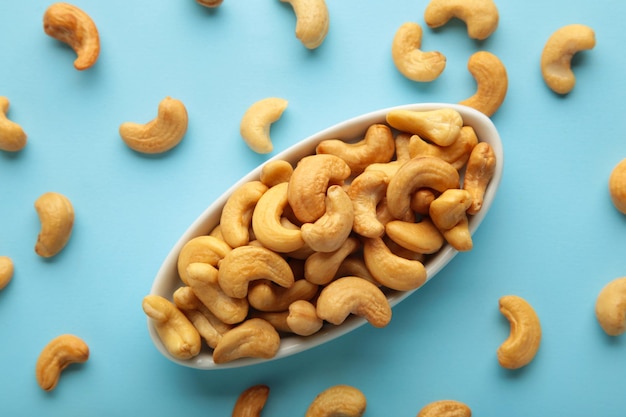 Cashew-Nüsse auf weißem Teller auf blauem Hintergrund. Ansicht von oben.