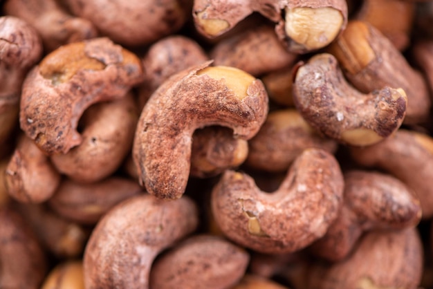 Cashew-Nüsse mit Schale in einem Teller auf Holztablett und Tischhintergrund gesunder Rohkostteller