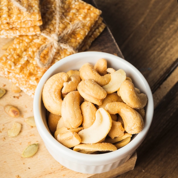 Cashew-Nüsse-Schalen mit Sesam-Energieriegel auf Schneidebrett