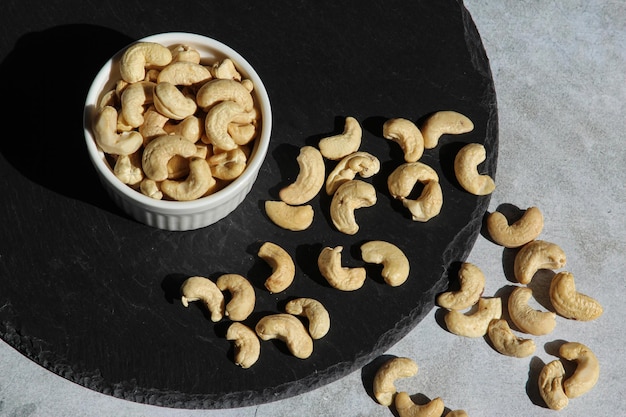 Cashewnüsse auf der schwarzen Steinplatte auf dem Zementhintergrund Draufsicht