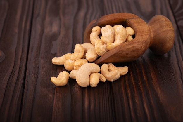 Cashewnüsse in der Holzschaufel, auf hölzernem Hintergrund. Geröstete Cashewnüsse.