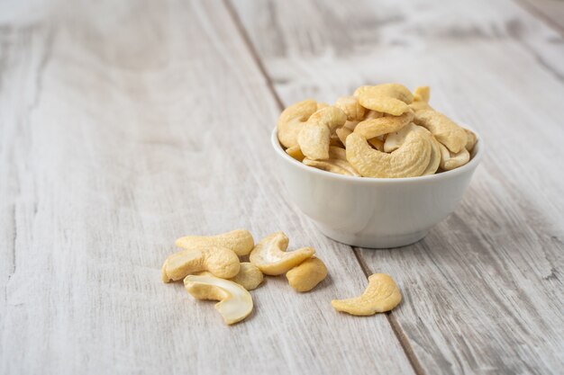 Cashewnüsse in der weißen Schüssel auf hellem Holztisch.