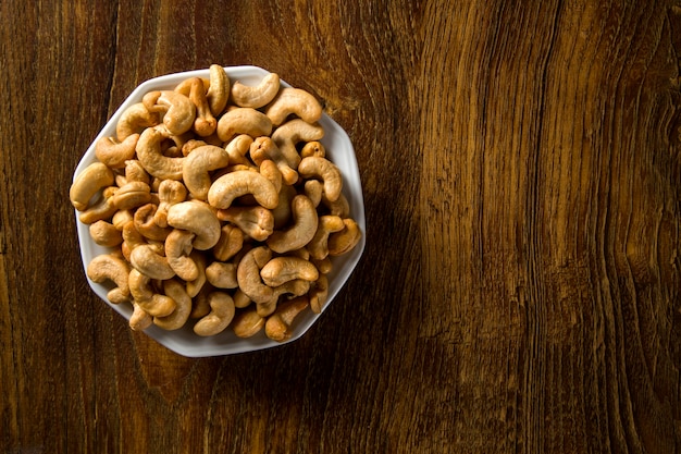 Cashewnüsse in der weißen Schüssel auf Holzhintergrund