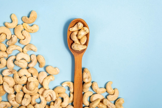 Cashewnüsse in einem Holzlöffel auf blauem Hintergrund