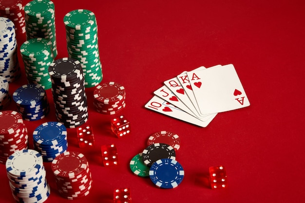 Casino-Glücksspiel-Poker-Ausrüstung und Unterhaltungskonzept - Nahaufnahme von Spielkarten und Chips auf rotem Hintergrund. Royal Flush Herz. Casino-Hintergrund. Platz kopieren. Stillleben