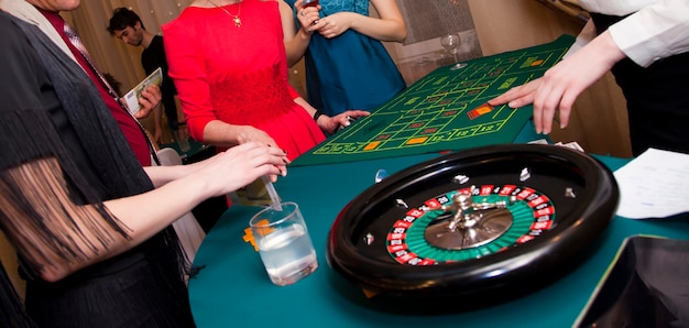 Casino zu Hause. Männer und Frauen spielen Roulette. Machen Sie Wetten mit Geld und Chips auf Zahlen. Grünes Tuch des Spieltisches. Glücksspiele für Erwachsene. Alle Wetten werden akzeptiert, es gibt keine Wetten mehr