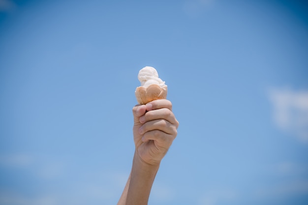 Casquinha de sorvete de creme de leite branco macio serve em dia quente de verão. Fundo do céu azul