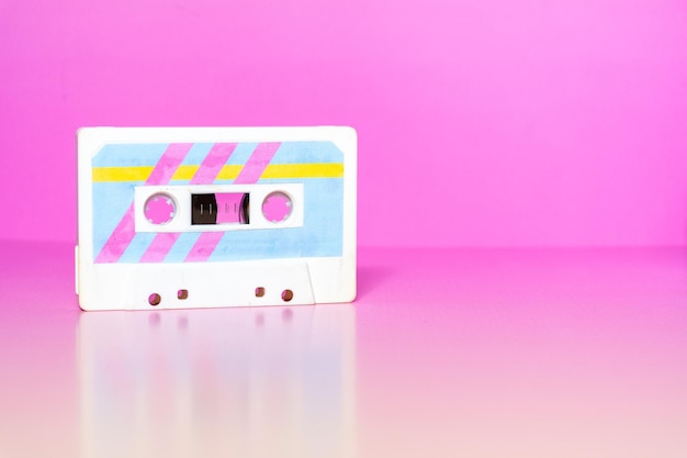 Cassete de áudio com rótulos retro coloridos em fundo fuchsia