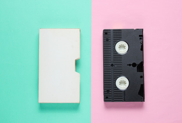 Cassete de vídeo retrô com tampa na superfície do papel de cor.