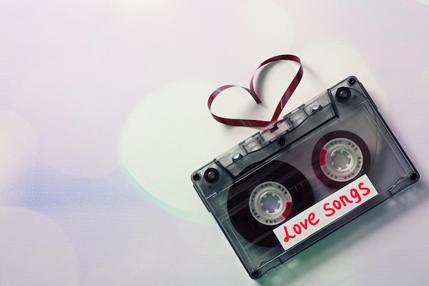 Cassette de audio con cinta magnética en forma de corazones sobre fondo claro