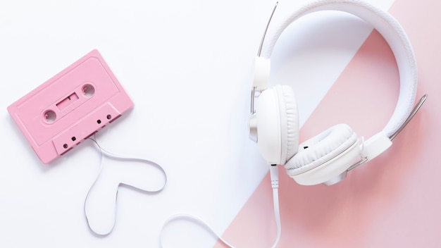 Foto cassette y auriculares sobre fondo blanco y rosa