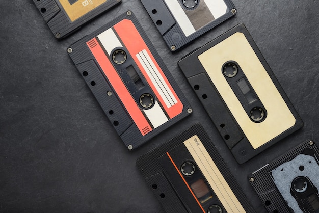 Cassettes compactos de cinta de audio negro antiguo sobre fondo de pizarra negra