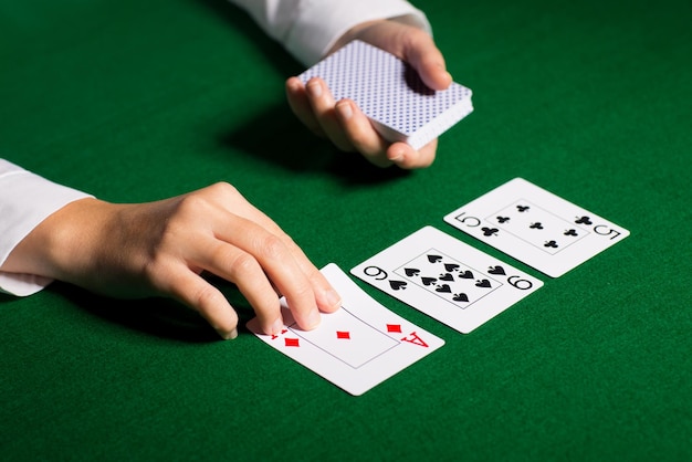 cassino, jogos de azar, pôquer, pessoas e conceito de entretenimento - close-up do negociante de holdem com cartas de baralho