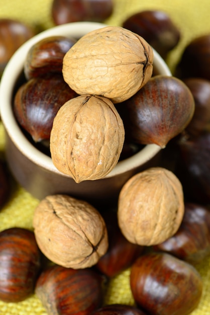 Castañas y nueces portuguesas en maceta de cerámica sobre yute amarillo