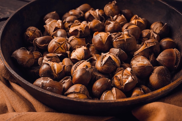 Castanhas assadas em uma panela de ferro vista superior da mesa de madeira sem estilo rústico de pessoas