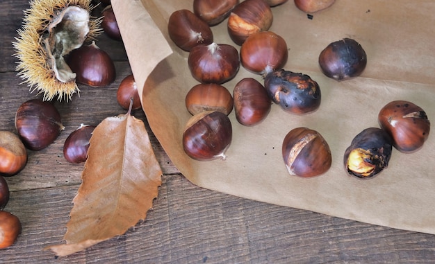 Castanhas assadas no papel sobre um papel sobre uma mesa de madeira