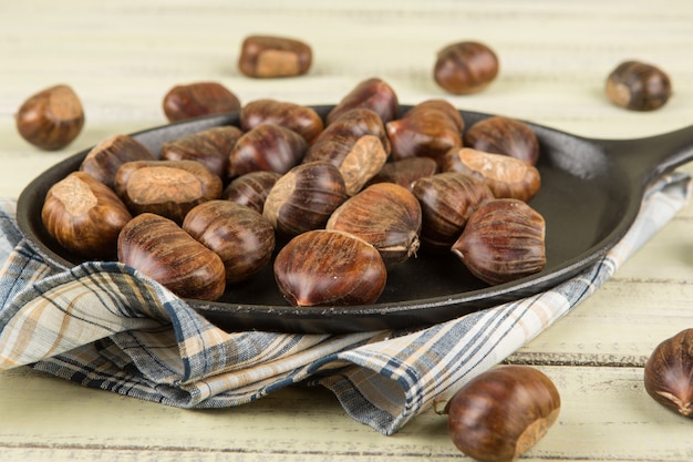 Castanhas em uma panela sobre uma madeira.