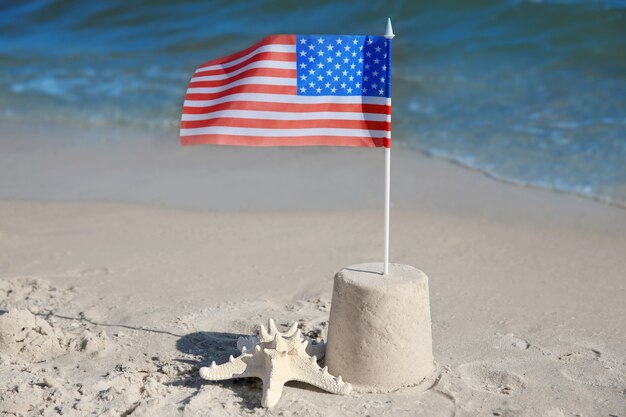 Castelo de areia com bandeira americana na praia