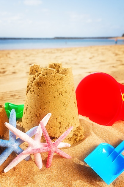 Castelo de areia com starfush na praia ensolarada de verão