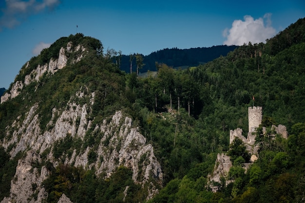 Castelo romântico no topo de uma colina em um vale montanhoso nos alpes da suíça, com um céu azul ao fundo, uma pequena vila sob a rocha