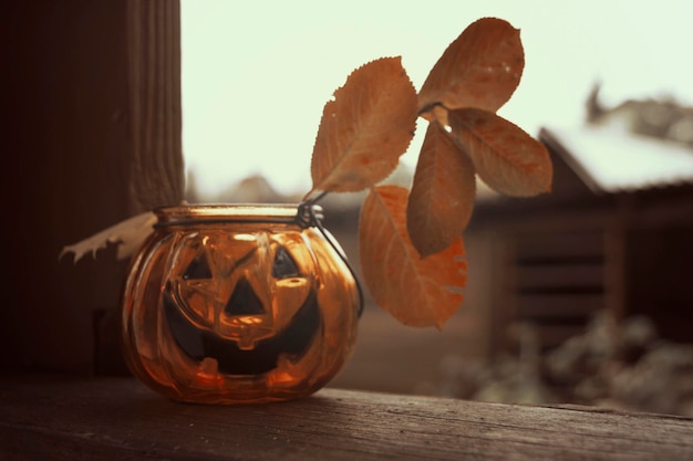 Foto castiçal de vidro de abóbora de halloween rindo com folhas de outono
