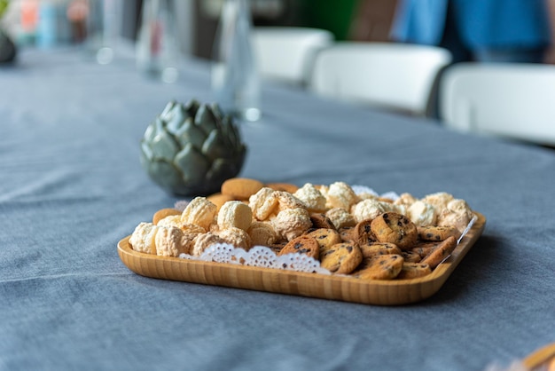 Castiçal em forma de flor há uma placa de madeira com três tipos de biscoitos em uma mesa