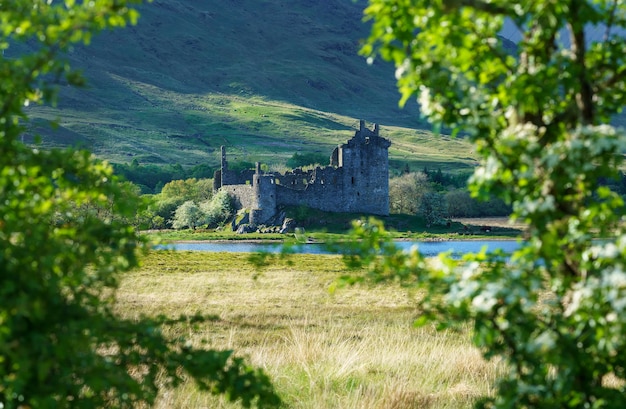 Foto el castillo de kilchurn, al cuidado del entorno histórico de escocia, es una estructura en ruinas en una península rocosa en loch awe en penumbra, argyll and bute, escocia