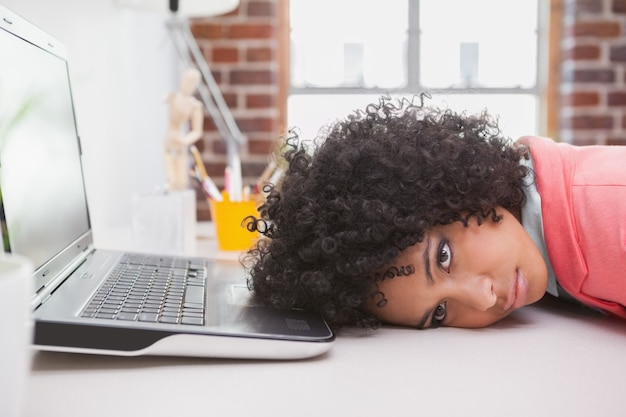 Casual empresaria descansando la cabeza en el escritorio