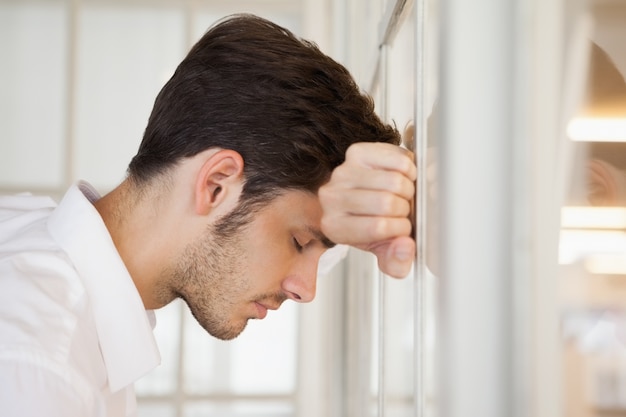 Foto casual empresario preocupado apoyado contra la ventana