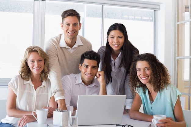 Casual equipo de negocios sonriente con una reunión usando la computadora portátil