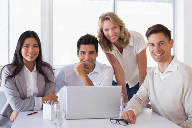 Casual equipo de negocios sonriente con una reunión usando la computadora portátil