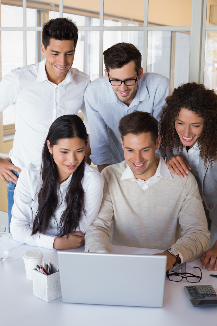 Foto casual equipo de negocios sonriente con una reunión usando la computadora portátil
