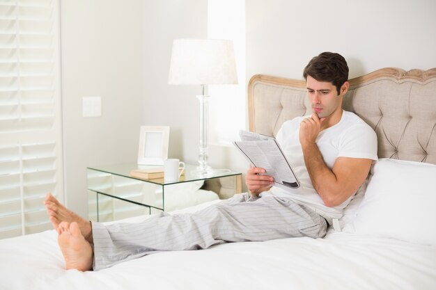 Casual hombre leyendo el periódico en la cama