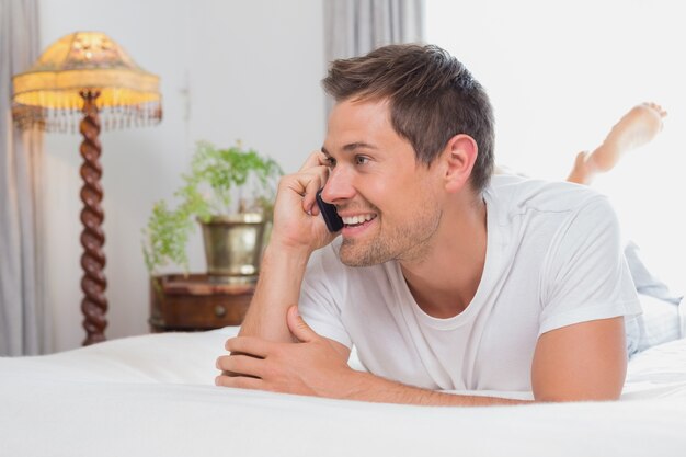 Casual hombre relajado usando teléfono móvil en la cama