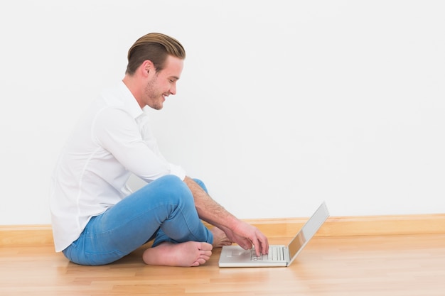 Casual hombre sentado en el piso usando laptop