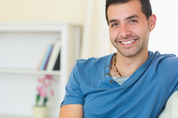 Foto casual hombre sonriente relajante en el sofá mirando a la cámara