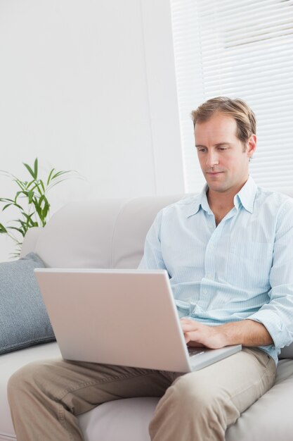 Casual hombre usando la computadora portátil en el sofá