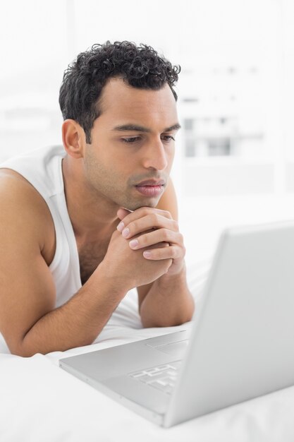 Casual hombre usando laptop en la cama